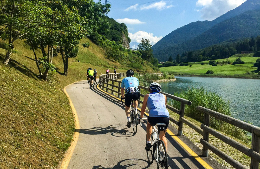 Cyclists ride alongside a lakeside country lane