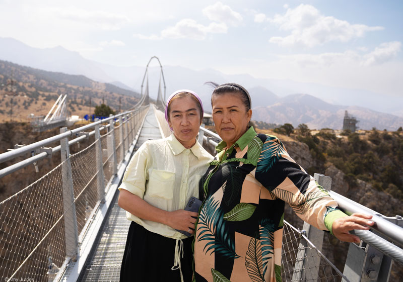 Two women stand on a suspension bridge in Uzbekistan