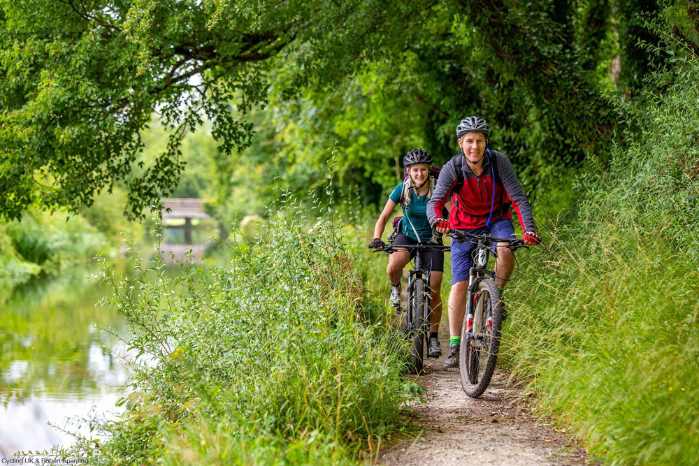 Two mountain bikers on a riverside trail